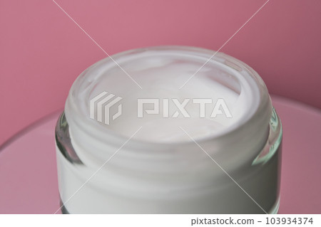 Glass jar with white face cream moisturiser on pink background. Glass jar with white face cream moisturiser on pink background. 103934374