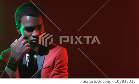 Man contemplation. Problem solution. Neon light puzzled concerned pensive gentleman in red tuxedo suit on dark empty space background. 103935315