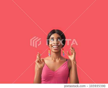 Good luck. Wish gesture. Opportunity chance. Inspired happy curious cheerful woman with crossed fingers looking up at empty space isolated on pink advertising background. 103935390