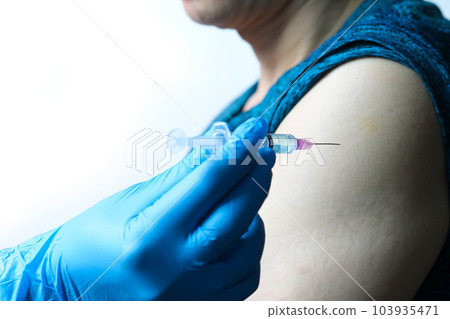 doctor's hand holds a syringe and a blue vaccine bottle at the hospital. Health and medical concepts. doctor's hand holds a syringe and a blue vaccine bottle at the hospital. Health and medical concepts. 103935471