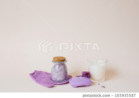 Spa care with natural soap, sea salt, washcloth glove for body care, lilac flowers and a candle on a light background with copy space Spa care with natural soap, sea salt, washcloth glove for body care, lilac flowers and a candle on a light background with copy space 103935587