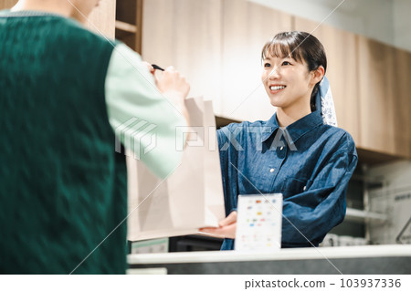 一位女店員將紙袋遞給購物者 103937336