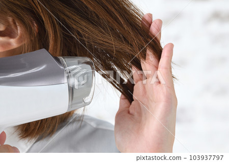 A woman's hand drying her hair with a hair dryer 103937797