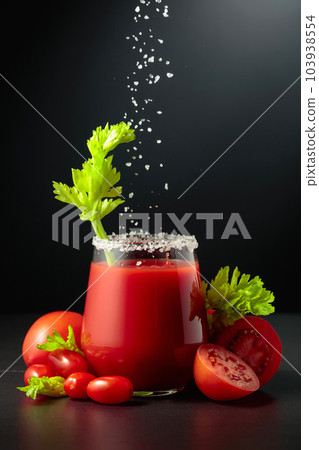 Sea salt is poured into a glass of tomato juice with celery. Sea salt is poured into a glass of tomato juice with celery. 103938554