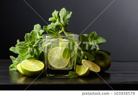 Cocktail Mojito with ice, lime, and mint on a black background. Cocktail Mojito with ice, lime, and mint on a black background. 103938579
