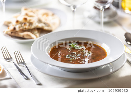 Italian vegetable minestrone soup with fresh herbs on top and pizza dough as a side dish 103939980