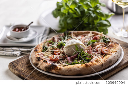 Freshly baked pizza with ham, ruccola and buffalo mozzarella Freshly baked pizza with ham, ruccola and buffalo mozzarella 103940004