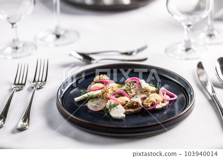A modern twist on duck liver pate presented with veggies on a dark plate on a restaurant table A modern twist on duck liver pate presented with veggies on a dark plate on a restaurant table 103940014