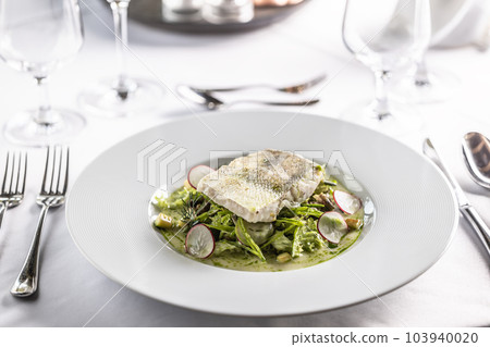 Restaurant serves cog fillet with green salad leaves and raddish in a deep plate Restaurant serves cog fillet with green salad leaves and raddish in a deep plate 103940020