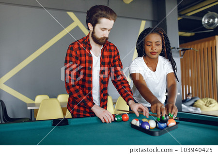 Black girl in a white t-shirt. Couple playing a billiard 103940425