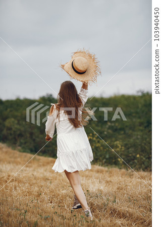 Woman in a summer field. Lady in a white dress. Girl on a sunset background. 103940450