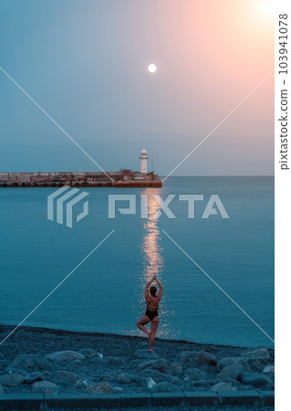 Woman The full moon rises to the lighthouse, the lunar path along the sea leads to the woman. Woman The full moon rises to the lighthouse, the lunar path along the sea leads to the woman. 103941078