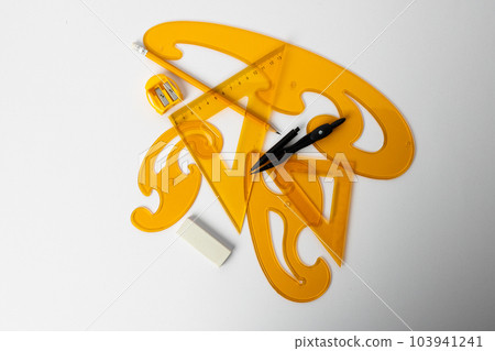 Close up of yellow rulers, compass and sharpener on white background Close up of yellow rulers, compass and sharpener on white background 103941241