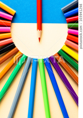 Close up of multi coloured pencils in circle and copy space on blue and yellow background Close up of multi coloured pencils in circle and copy space on blue and yellow background 103941298