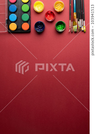 Close up of paints and brushes with copy space on red background Close up of paints and brushes with copy space on red background 103941513