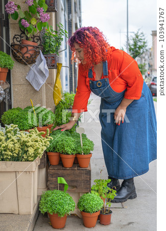 Young woman choosing manjerico plant in street shop 103941767