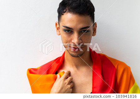 Portrait of happy biracial transgender man holding rainbow flag on white background 103941816