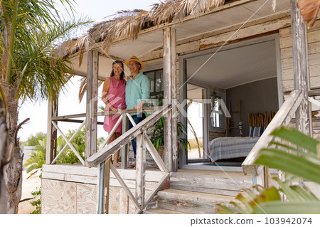 Caucasian happy senior couple standing by railing in balcony at wooden cottage, copy space Caucasian happy senior couple standing by railing in balcony at wooden cottage, copy space 103942074