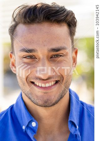 Close-up portrait of handsome caucasian young man with brown eyes smiling and looking at camera 103942145