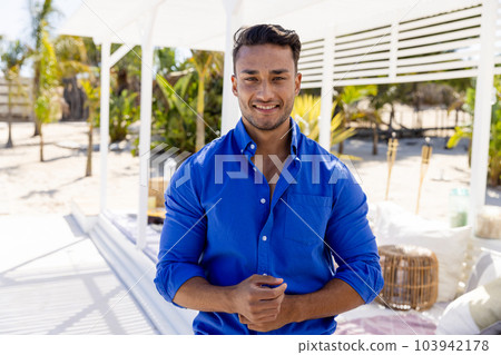 Portrait of handsome caucasian young man wearing blue shirt standing at tourist resort, copy space 103942178