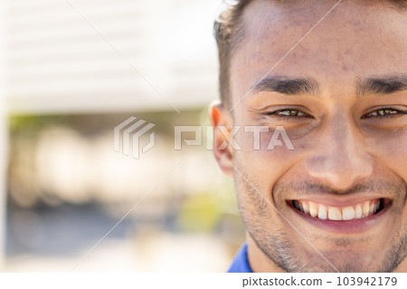 Close-up portrait of handsome caucasian young man with brown eyes smiling and looking at camera 103942179