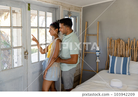 Side view of caucasian young couple looking through window while standing in hotel, copy space Side view of caucasian young couple looking through window while standing in hotel, copy space 103942209