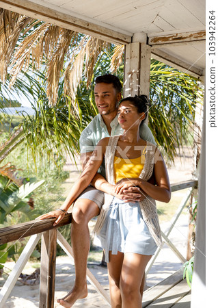 Caucasian young man embracing woman from back and looking away in balcony at cottage 103942264
