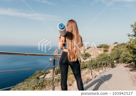 Fitness woman sea. Outdoor workout on yoga mat roller in park near to ocean beach. Female fitness pilates yoga routine concept. Healthy lifestyle. Happy fit woman exercising with rubber band in park. 103942527