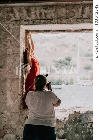 Woman travel portrait. Happy woman with long hair looking at camera and smiling. Close up portrait cute woman in a res long dress posing on backdrop of old travel city near sea 103942548