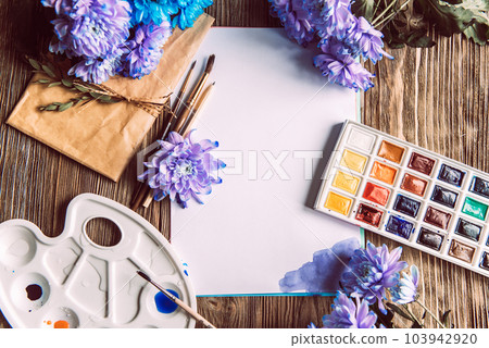 Palette of watercolor paints, brushes and paper for a water color on wooden background, close up. Flat lay, spring background with copy space Palette of watercolor paints, brushes and paper for a water color on wooden background, close up. Flat lay, spring background with copy space 103942920