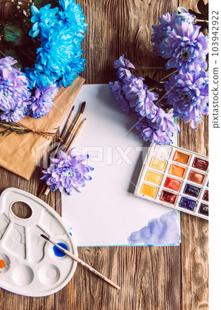 Palette of watercolor paints, brushes and paper for a water color on wooden background, close up. Flat lay, spring background with copy space 103942922