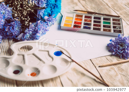 Palette of watercolor paints, brushes and paper for a water color on wooden background, close up. Flat lay, spring background with copy space 103942977
