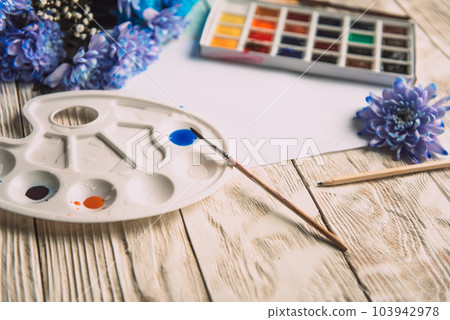 Palette of watercolor paints, brushes and paper for a water color on wooden background, close up. Flat lay, spring background with copy space Palette of watercolor paints, brushes and paper for a water color on wooden background, close up. Flat lay, spring background with copy space 103942978