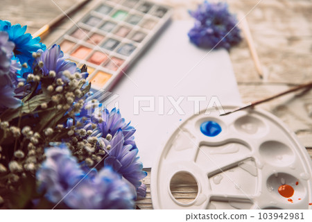 Palette of watercolor paints, brushes and paper for a water color on wooden background, close up. Flat lay, spring background with copy space Palette of watercolor paints, brushes and paper for a water color on wooden background, close up. Flat lay, spring background with copy space 103942981