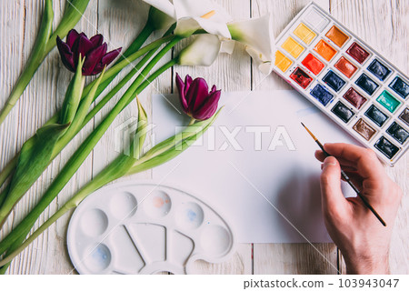 Palette of watercolor paints, brushes and paper for a water color on wooden background, close up. Flat lay, spring background with copy space Palette of watercolor paints, brushes and paper for a water color on wooden background, close up. Flat lay, spring background with copy space 103943047