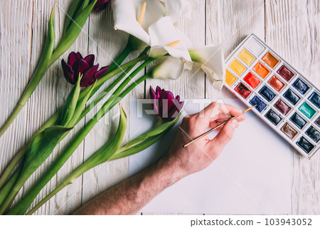 Palette of watercolor paints, brushes and paper for a water color on wooden background, close up. Flat lay, spring background with copy space Palette of watercolor paints, brushes and paper for a water color on wooden background, close up. Flat lay, spring background with copy space 103943052