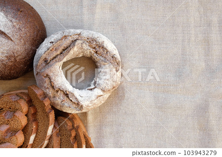 Baked bread. Loaf of Bread. Fresh Bakery Products on Wooden Board. Healthy Food Concept. Top View. Flat lay. Slices of Homemade Sourdough Bread with Flour on Rustic Linen Background. Wheat Spikes 103943279