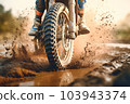 Close-up shot of the front wheel of a motocross bike riding along a muddy dirt track - Generative AI 103943374