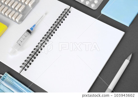 Gray modern doctor desk table with mask, notepad, syringe, sanitizer and supplies. Copy space, flat lay. Top view. Medicine and healthcare, cardiology, medical education. Blank white sheet for text Gray modern doctor desk table with mask, notepad, syringe, sanitizer and supplies. Copy space, flat lay. Top view. Medicine and healthcare, cardiology, medical education. Blank white sheet for text 103943602