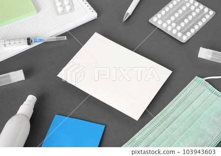 Gray modern doctor desk table with mask, notepad, syringe, sanitizer and supplies. Copy space, flat lay. Top view. Medicine and healthcare, cardiology, medical education. Blank white sheet for text Gray modern doctor desk table with mask, notepad, syringe, sanitizer and supplies. Copy space, flat lay. Top view. Medicine and healthcare, cardiology, medical education. Blank white sheet for text 103943603