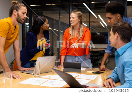 Diverse creative colleagues in discussion brainstorming with laptops and notes in meeting room 103943915