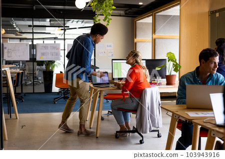 Diverse male and female colleagues in discussion using laptop in office 103943916