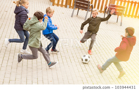 Kids playing football outdoors 103944431