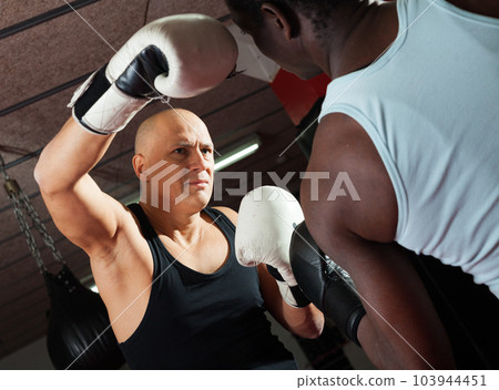 Two athlete men in sportswear exercising boxing sparring in the hall Two athlete men in sportswear exercising boxing sparring in the hall 103944451