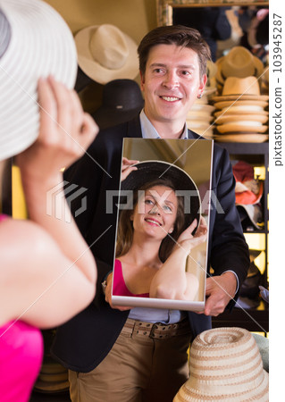 guy holding mirror and showing female his reflection in hats shopping mall guy holding mirror and showing female his reflection in hats shopping mall 103945287