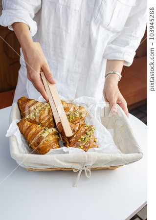 Woman plucks croissant from basket with wooden spikes Woman plucks croissant from basket with wooden spikes 103945288