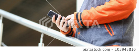 Smartphone in hand of young man standing on stairs outdoors Smartphone in hand of young man standing on stairs outdoors 103945816