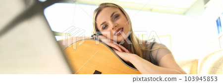 Young beautiful woman playing acoustic guitar at home Young beautiful woman playing acoustic guitar at home 103945853