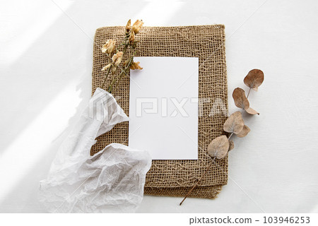 Fashionable stock stationery background - white card for lettering and dry plants and flowers on a white table. Fashionable stock stationery background - white card for lettering and dry plants and flowers on a white table. 103946253
