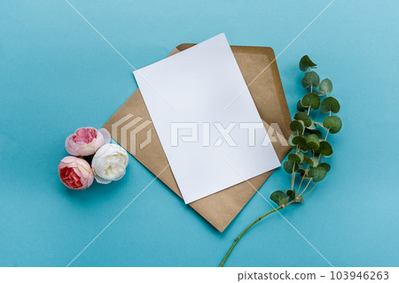 A kraft paper envelope with a white blank card flowers on a blue background. Postcard preparation 103946263